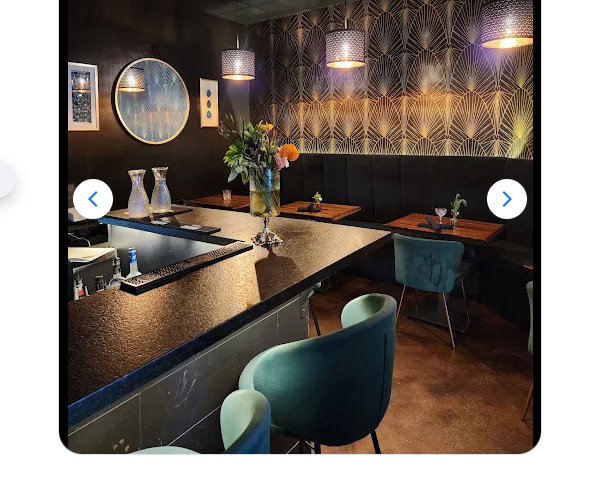 Existing bar with its black countertop and green upholstered chairs